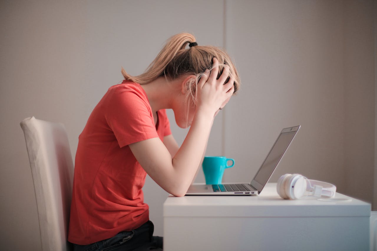 hero-img-01 Young woman feeling stressed while studying at home with a laptop and coffee cup.