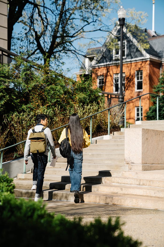 gallery-6 Two young adults walking up outdoor stairs surrounded by greenery and buildings.