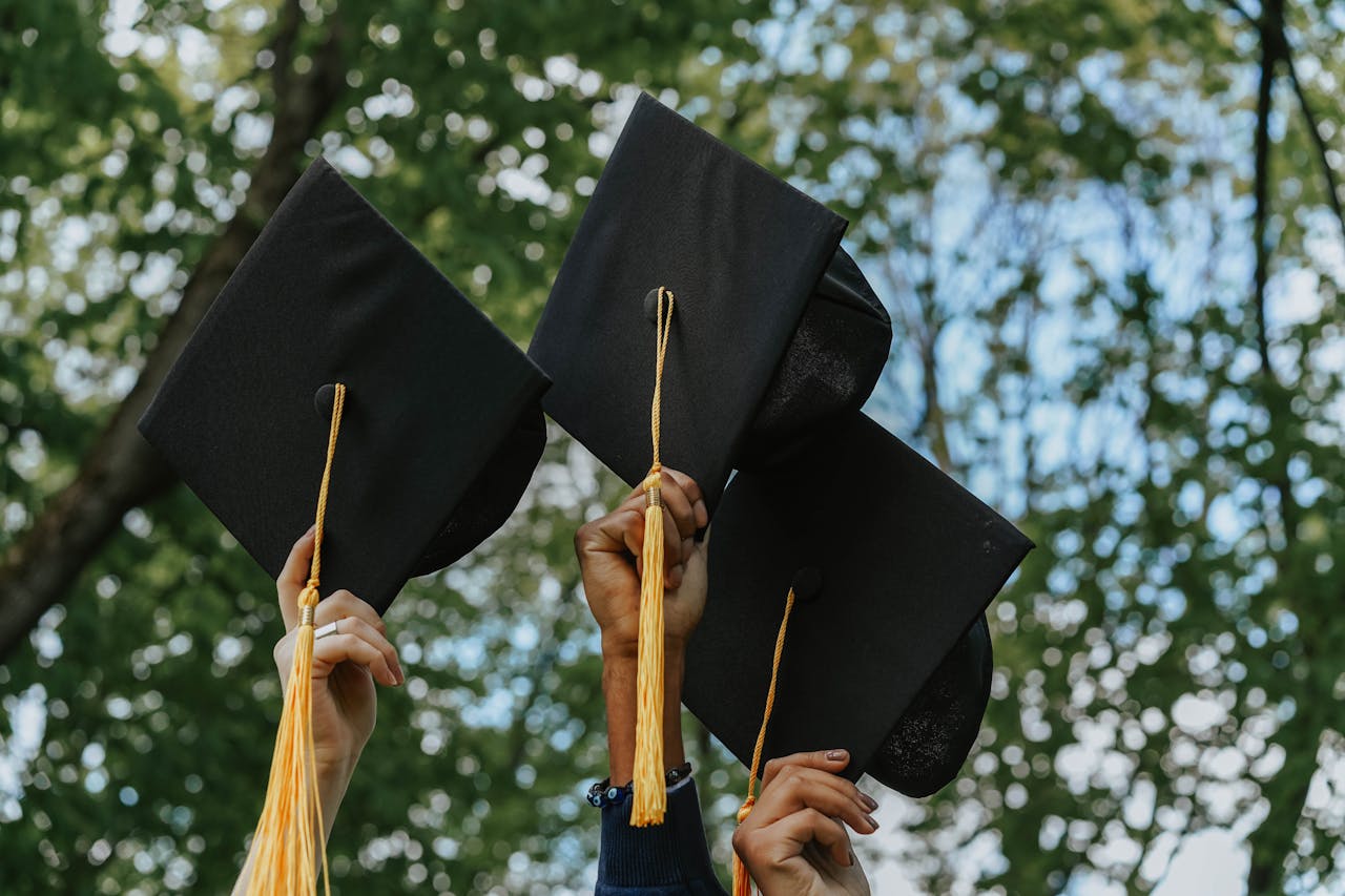 our-services-1 Three hands holding graduation caps in celebration, symbolizing success.